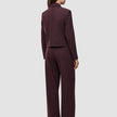 En kvinde set bagfra har den korte jakke Women Serene Short Jacket Berry Pinstripe på sammen med et par matchende bukser med brede ben.