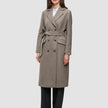 En kvinde iført en Women Wool Coat Greige – en knælang uldfrakke med dobbeltradet knaplukning og et matchende bindebælte.